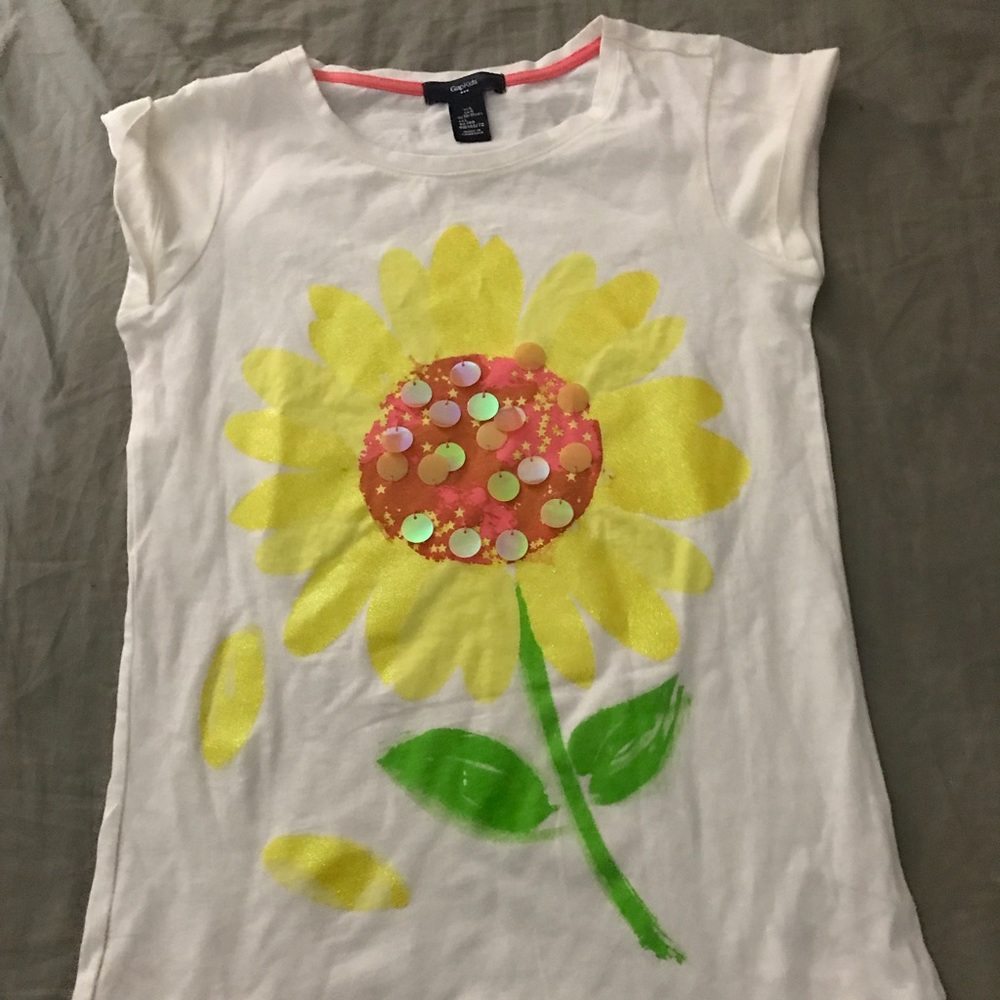 A white children’s tee shirt with a sunflower.